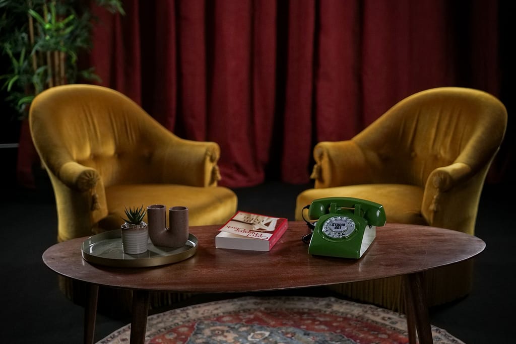 Vue d'ensemble des fauteuils jaunes et de la table basse avec objets déco et tapis rond