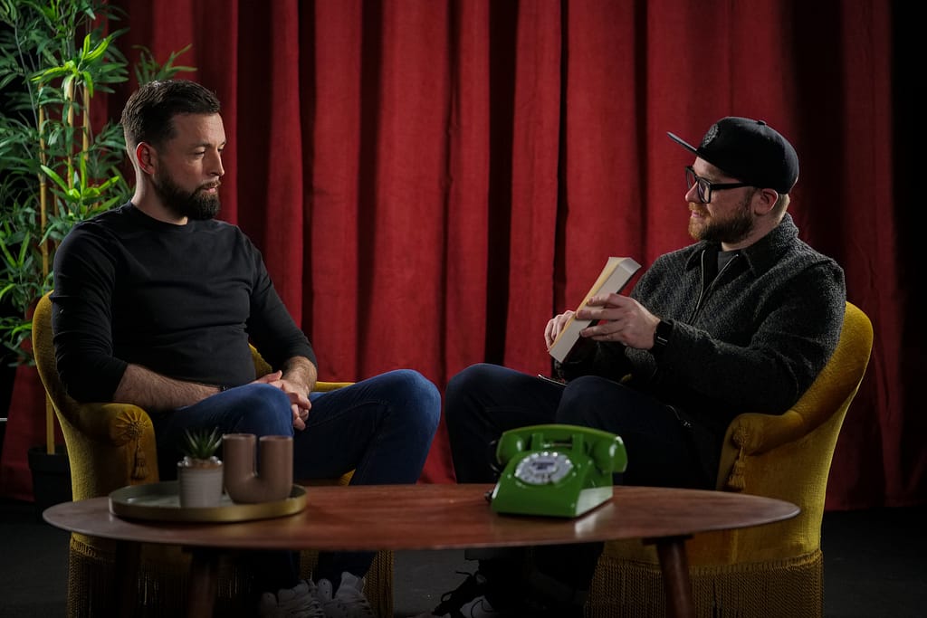 Plan serré d’une interview avec deux personnes assises, un livre à la main