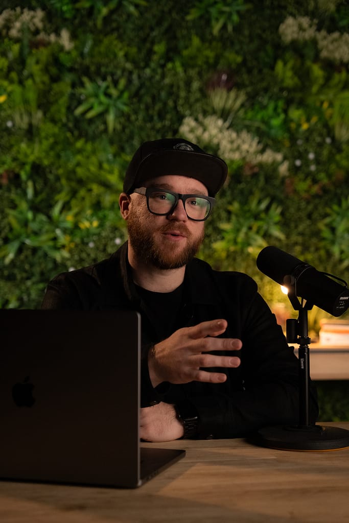 Setup podcast avec micro Shure, ordinateur portable et décor végétal L’Équilibre en arrière-plan